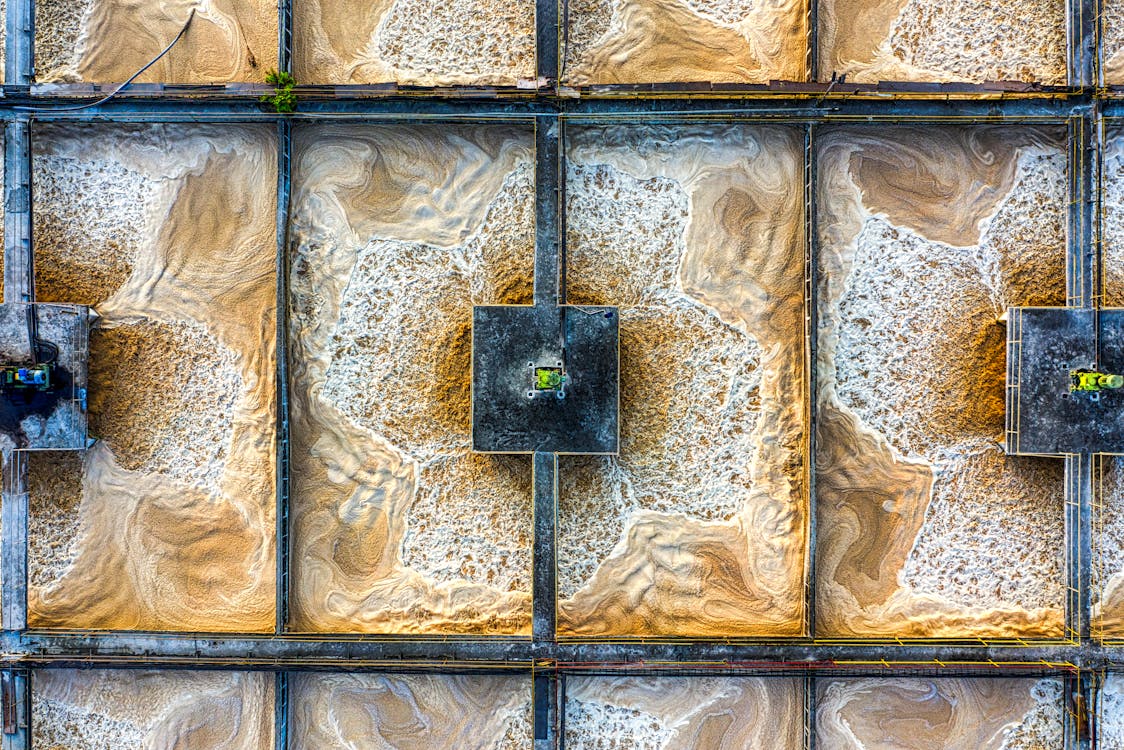 Aerial view of industrial wastewater treatment basins with visible aeration patterns used for odor control