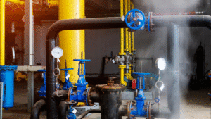 Industrial boiler system with pipes, valves, gauges, and visible steam indicating corrosion risk—highlighting the importance of boiler rust inhibitors.