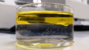 Oil and water phase separation in a petri dish, demonstrating chemical formulation effectiveness in emulsion breaking.