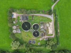Aerial view of a wastewater treatment plant showing multiple circular clarifiers and sedimentation tanks used in coagulation and flocculation processes for suspended solids removal.