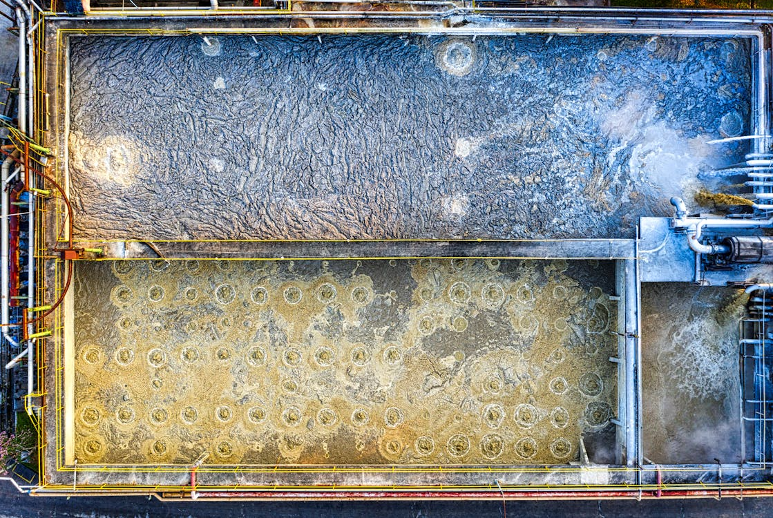 Aerial view of an industrial wastewater treatment facility showing active sludge and clarification tanks used in the coagulation and flocculation process to remove suspended solids.