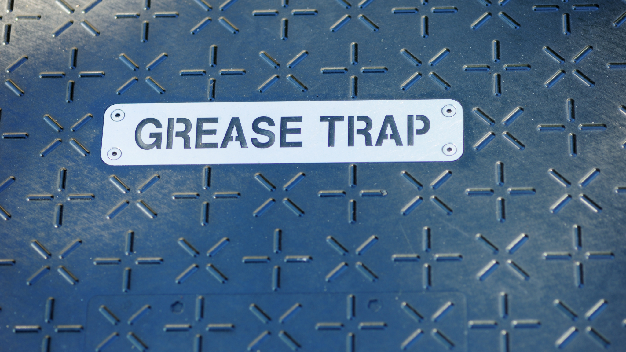 Metal cover labeled grease trap representing wastewater management system access point.