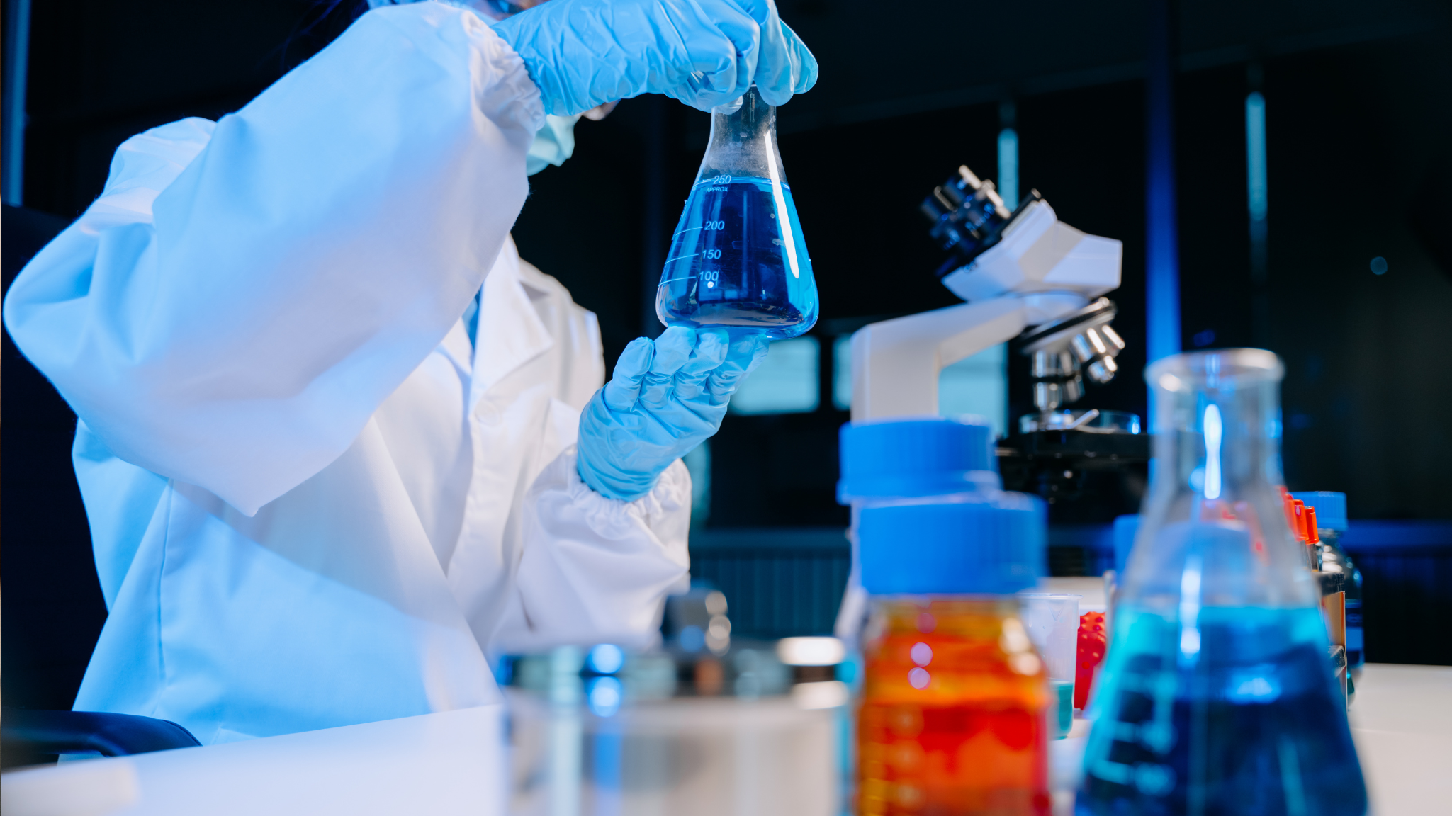 Technician analyzing blue liquid in a laboratory setting, representing precision and quality control in chemical blending services for industrial water treatment.