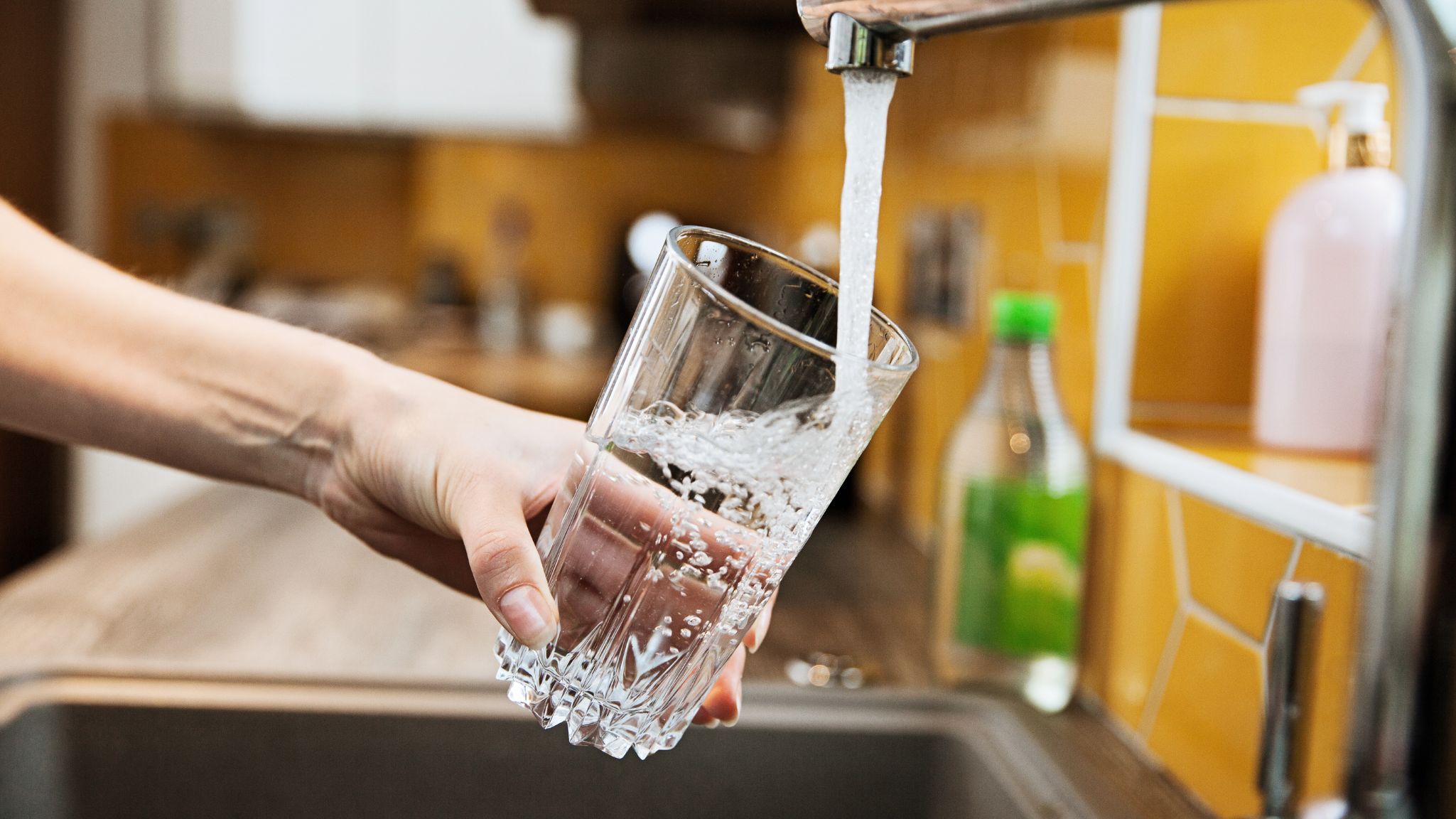 Safe, NSF-60 certified drinking water flowing from a tap into a glass after proper chemical treatment.