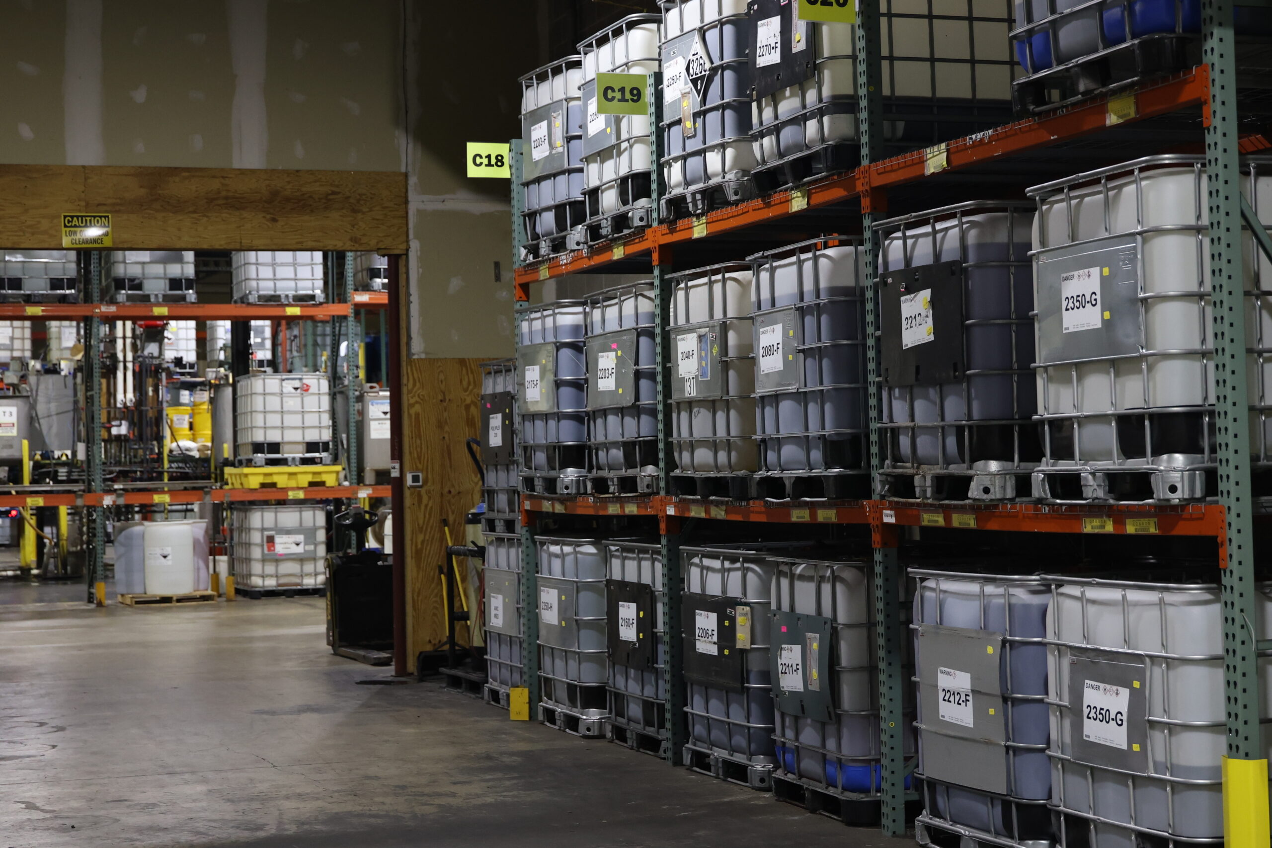 Chemical storage area with bulk chemical containers organized on industrial warehouse racking following safe storage best practices