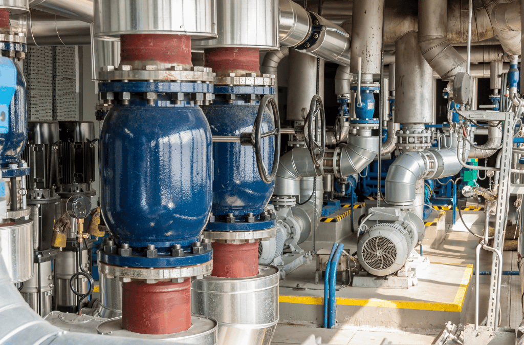 Industrial piping, valves, and pumps in a mechanical equipment room.