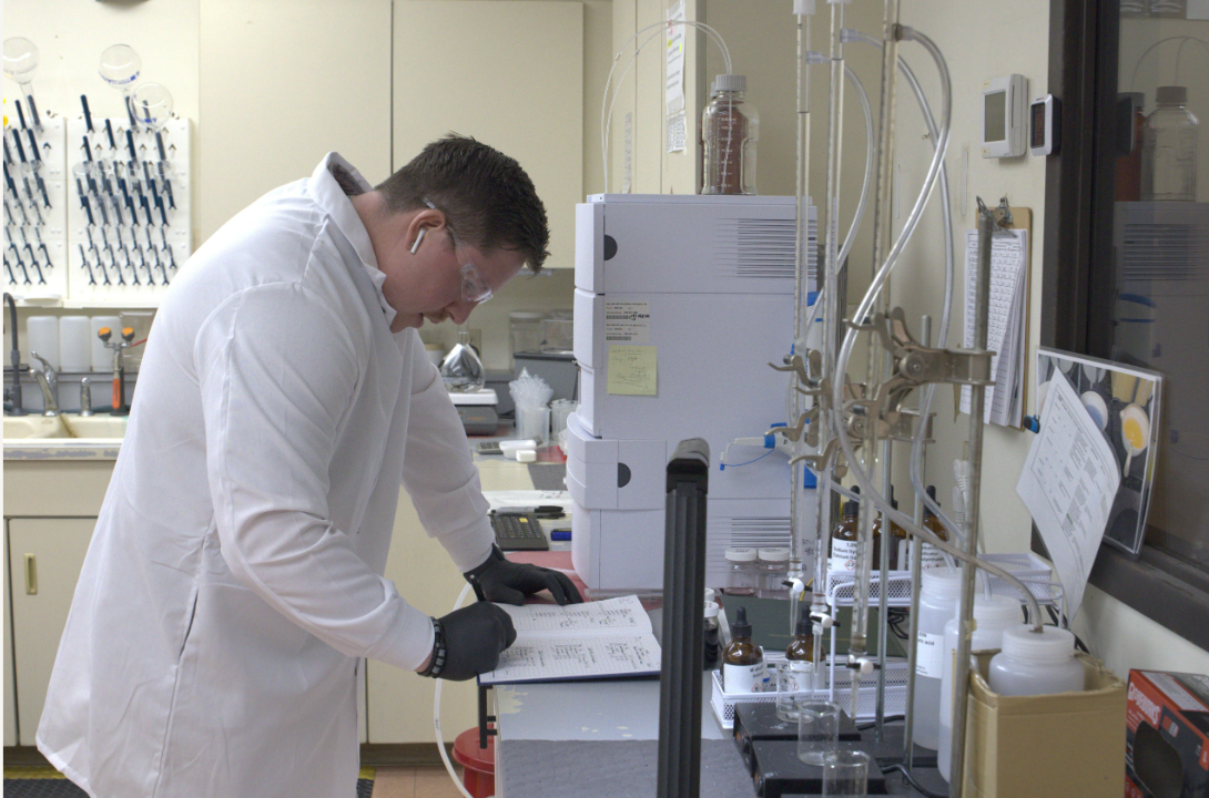 ETI laboratory technician reviewing records beside analytical testing equipment