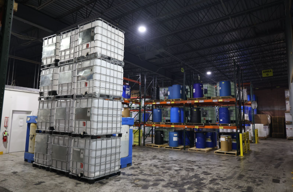 Stacked totes and drums on storage racks inside ETI’s water treatment chemical warehouse.